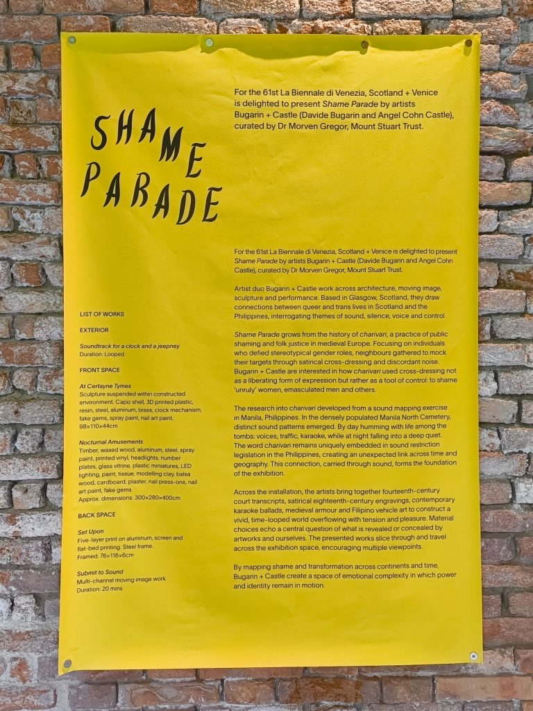Bright yellow exhibition information panel for Shame Parade mounted on an exposed brick wall, featuring artwork details, artist information and a list of works presented as part of Scotland + Venice at the Venice Biennale.